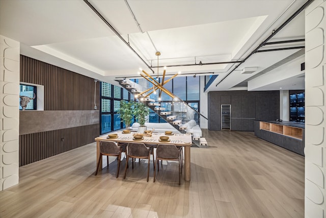 dining room featuring a notable chandelier, wood walls, and light hardwood / wood-style flooring