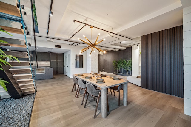 dining area with light hardwood / wood-style flooring and an inviting chandelier