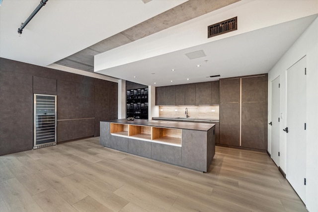 kitchen featuring light hardwood / wood-style floors, dark brown cabinets, sink, and beverage cooler