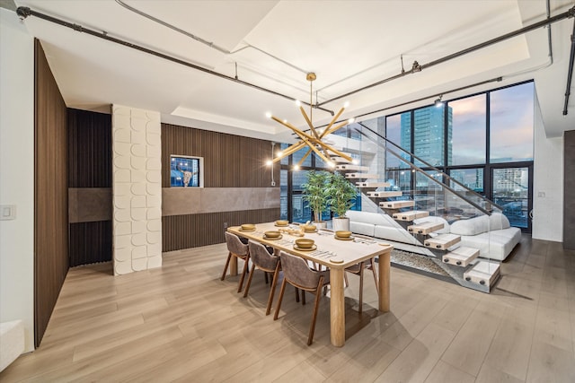 dining area featuring light hardwood / wood-style floors, wood walls, and a chandelier