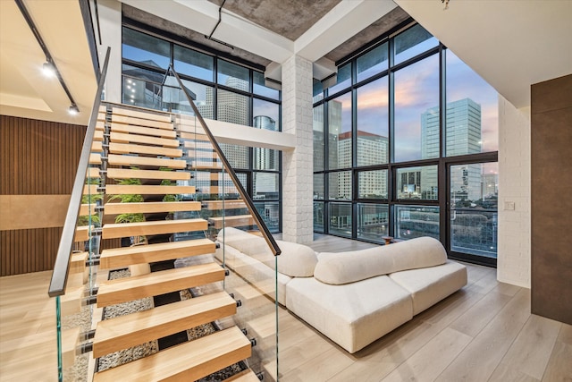 stairs with a wall of windows, wood-type flooring, a high ceiling, and wood walls