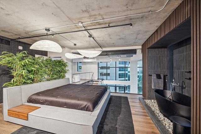 bedroom featuring a wall of windows and hardwood / wood-style flooring