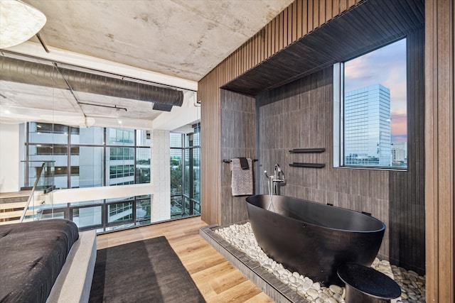 bathroom featuring a bathing tub, wood walls, and wood-type flooring