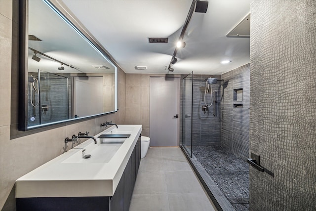 bathroom featuring toilet, a shower with shower door, vanity, and tile walls