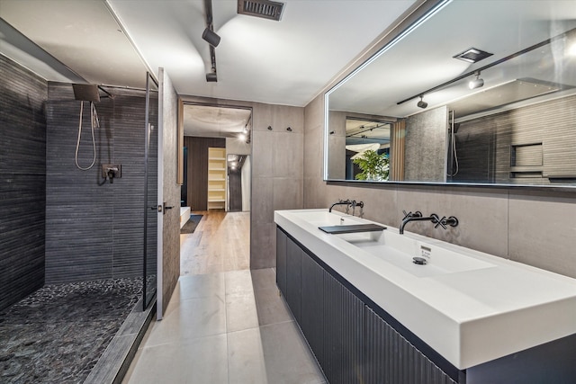 bathroom featuring tile walls, vanity, a tile shower, and wood-type flooring