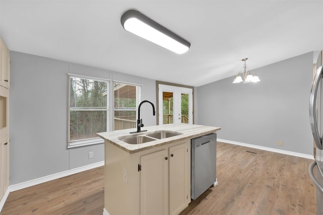 kitchen featuring light wood-type flooring, hanging light fixtures, sink, dishwasher, and a kitchen island with sink