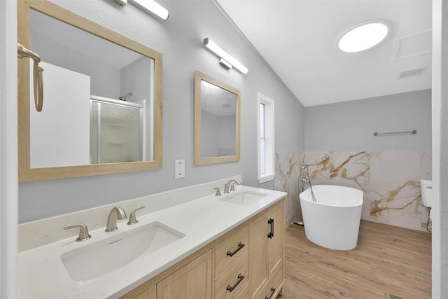 bathroom with lofted ceiling, tile walls, hardwood / wood-style flooring, vanity, and independent shower and bath