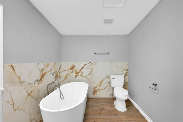 bathroom with crown molding, a bathtub, hardwood / wood-style flooring, and toilet