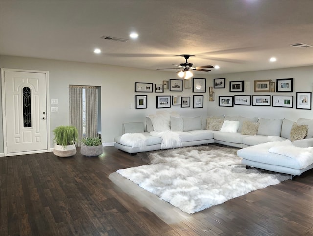 living room featuring dark wood-type flooring and ceiling fan