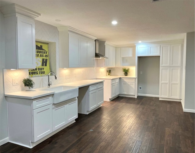 kitchen featuring white cabinetry, sink, backsplash, wall chimney range hood, and dark hardwood / wood-style flooring