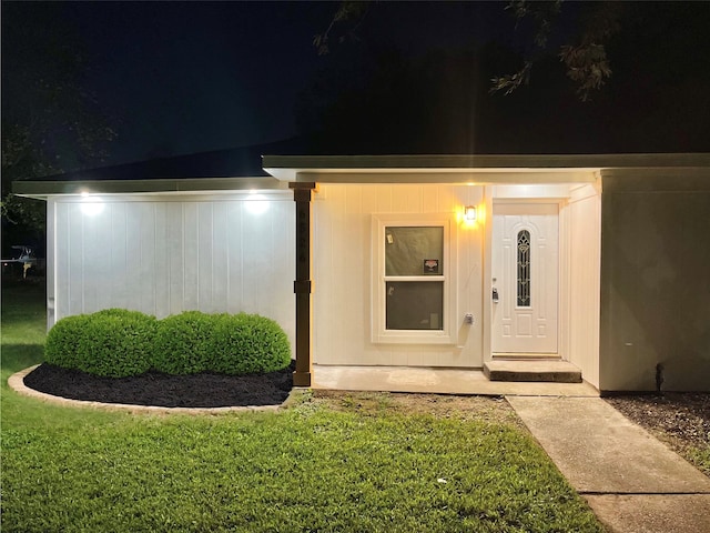 exterior entry at twilight featuring a lawn