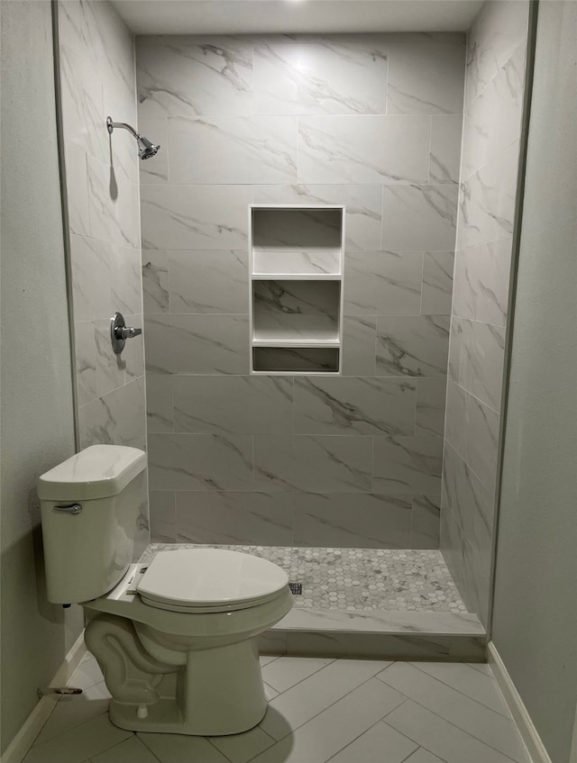 bathroom with toilet, tile patterned floors, and a tile shower