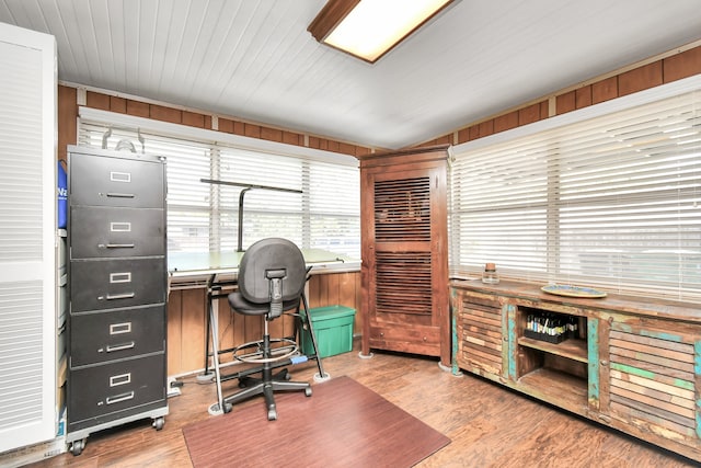 office featuring wood walls, light hardwood / wood-style floors, and vaulted ceiling