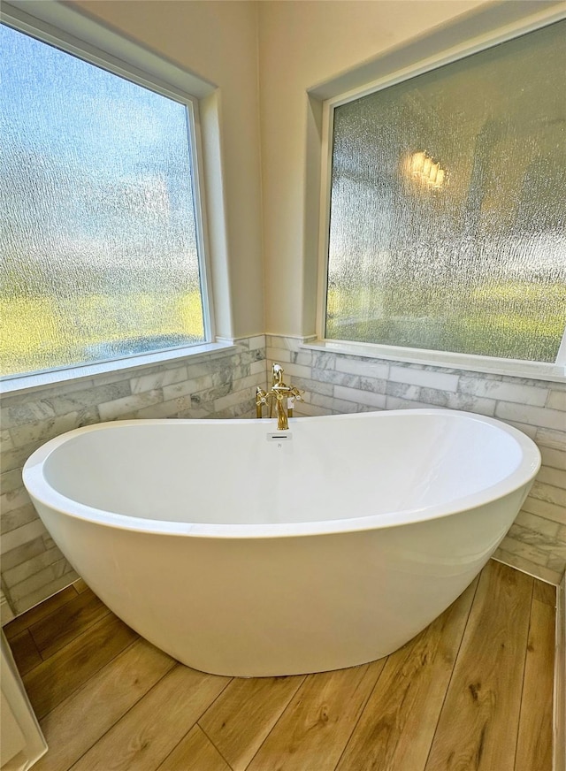 623 Barkaloo Rd, Baytown, TX 77521 - bathroom featuring a freestanding bath, tile walls, wainscoting, and wood finished floors