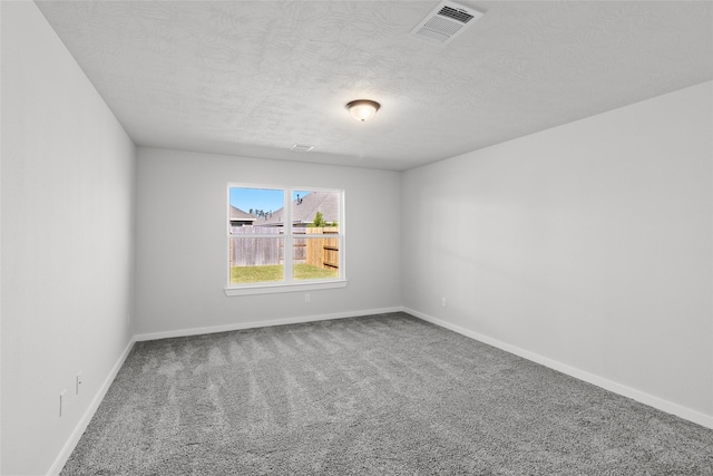 carpeted empty room featuring a textured ceiling