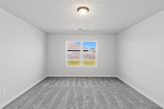 carpeted empty room with a textured ceiling