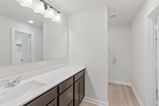 bathroom with hardwood / wood-style floors, vanity, and a shower with door