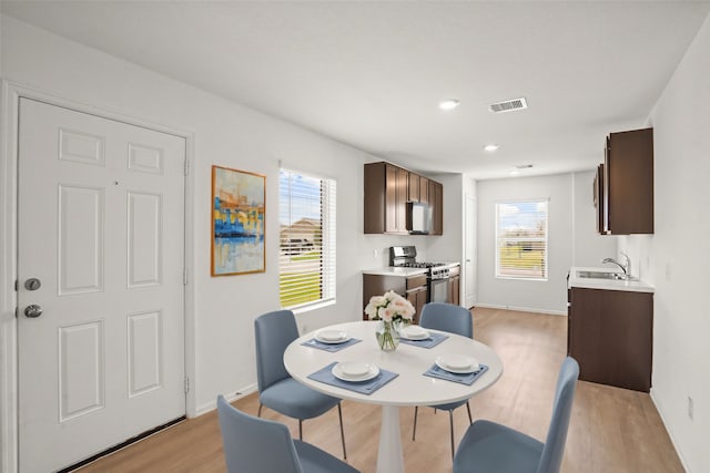 dining area featuring light hardwood / wood-style floors, a healthy amount of sunlight, and sink