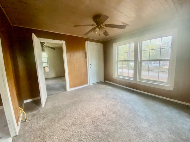 unfurnished bedroom featuring wood walls, light colored carpet, and ceiling fan