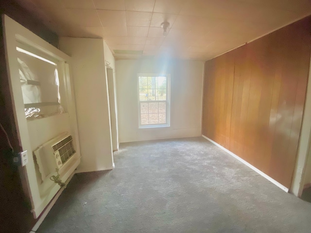 spare room featuring wooden walls, carpet flooring, and an AC wall unit