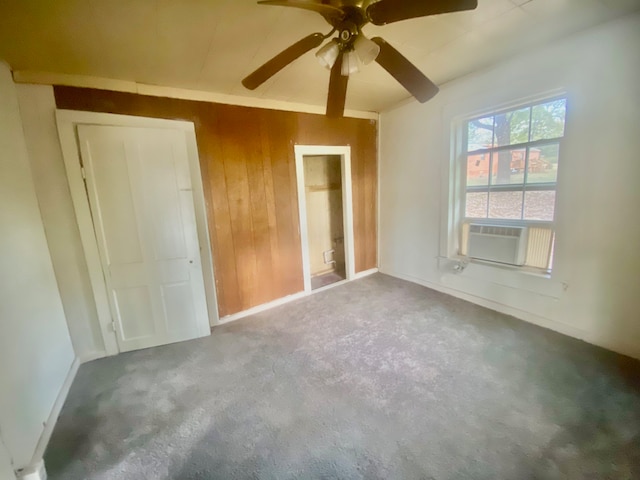 unfurnished bedroom with ceiling fan, cooling unit, carpet flooring, a closet, and wooden walls