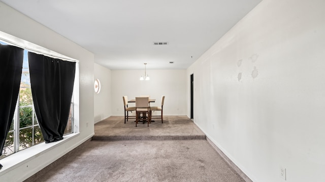 carpeted dining area with an inviting chandelier