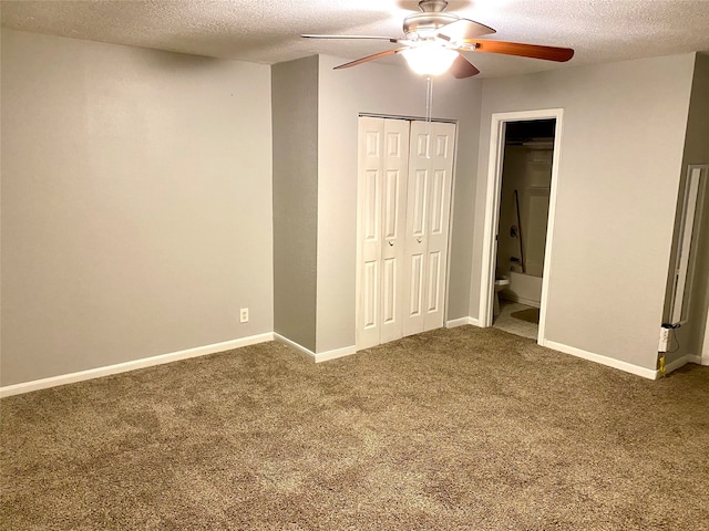 unfurnished bedroom with a textured ceiling, ensuite bathroom, carpet flooring, and ceiling fan