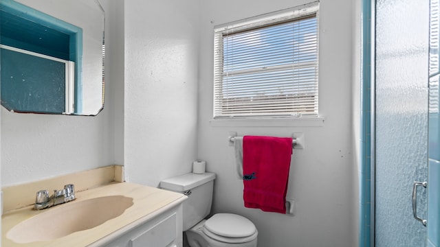 bathroom featuring a shower with door, vanity, and toilet