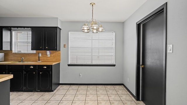 kitchen with hanging light fixtures, sink, an inviting chandelier, light tile patterned floors, and tasteful backsplash