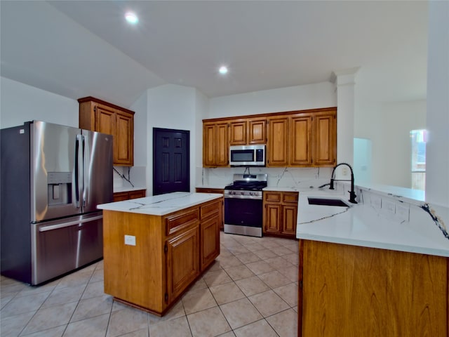 kitchen with sink, kitchen peninsula, appliances with stainless steel finishes, a kitchen island, and vaulted ceiling