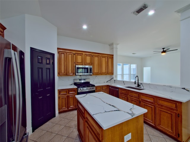 kitchen with appliances with stainless steel finishes, light tile patterned floors, sink, ceiling fan, and a center island