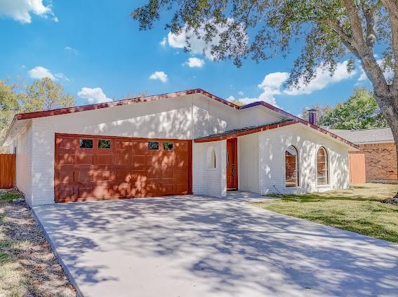7311 La Mesa Dr, Houston, TX 77083 - mediterranean / spanish house featuring an attached garage and driveway