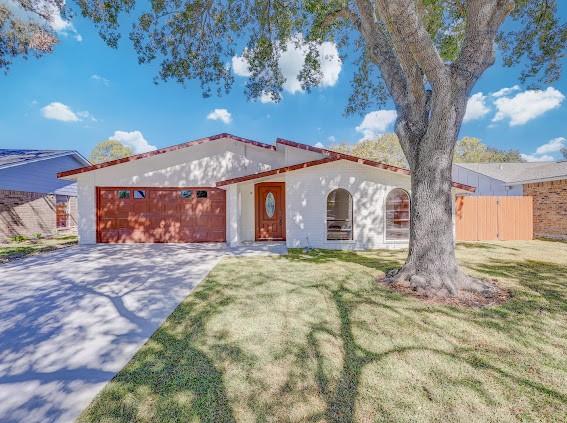 7311 La Mesa Dr, Houston, TX 77083 - mediterranean / spanish home with a garage, concrete driveway, and stucco siding