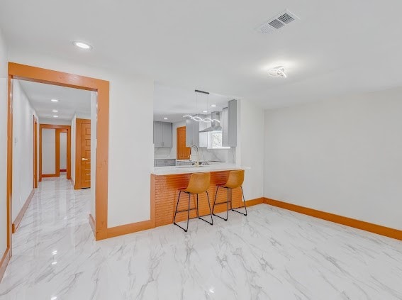 kitchen with a kitchen breakfast bar, kitchen peninsula, wall chimney exhaust hood, and sink