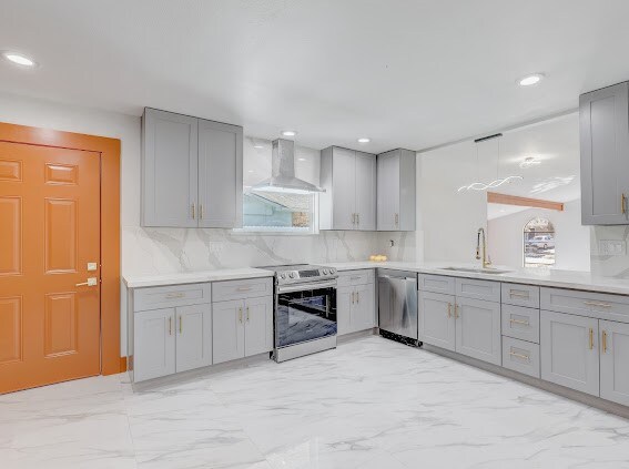 kitchen with appliances with stainless steel finishes, wall chimney exhaust hood, sink, and a wealth of natural light