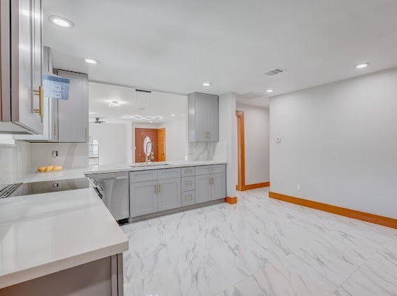 kitchen featuring sink, dishwasher, kitchen peninsula, and gray cabinetry