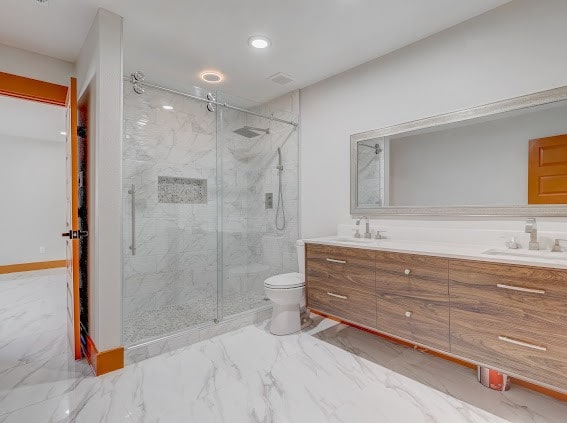 bathroom featuring vanity, toilet, and a shower with door