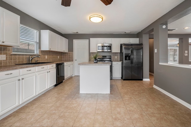 kitchen with decorative backsplash, stainless steel appliances, sink, a center island, and white cabinets