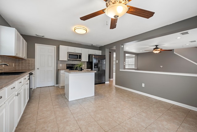 kitchen with backsplash, white cabinetry, black appliances, sink, and a center island