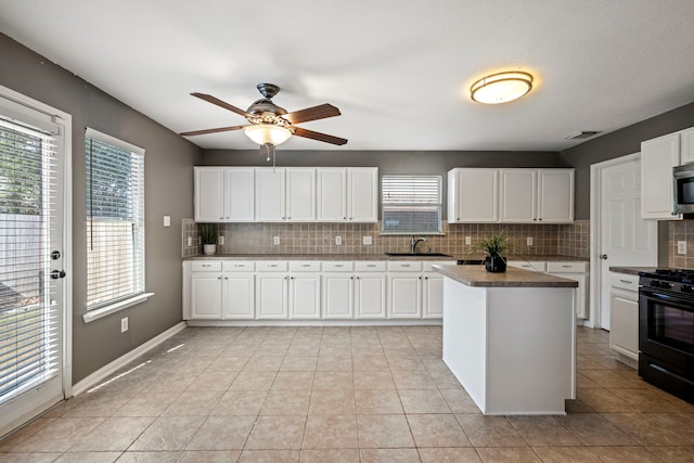 kitchen featuring decorative backsplash, black stove, white cabinetry, and light tile patterned floors