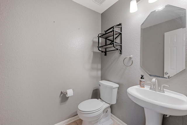 bathroom with sink, toilet, and tile patterned flooring