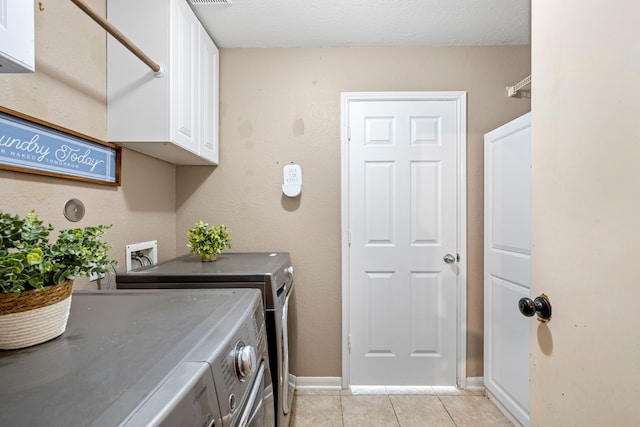 laundry room featuring cabinets, a textured ceiling, light tile patterned flooring, and separate washer and dryer