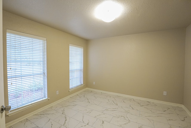 unfurnished room with a textured ceiling and a healthy amount of sunlight