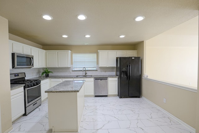 kitchen with light stone counters, backsplash, a kitchen island, white cabinetry, and stainless steel appliances