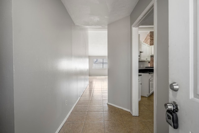 corridor featuring a textured ceiling and light tile patterned floors