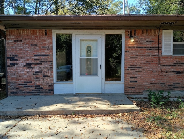 view of exterior entry with a patio area