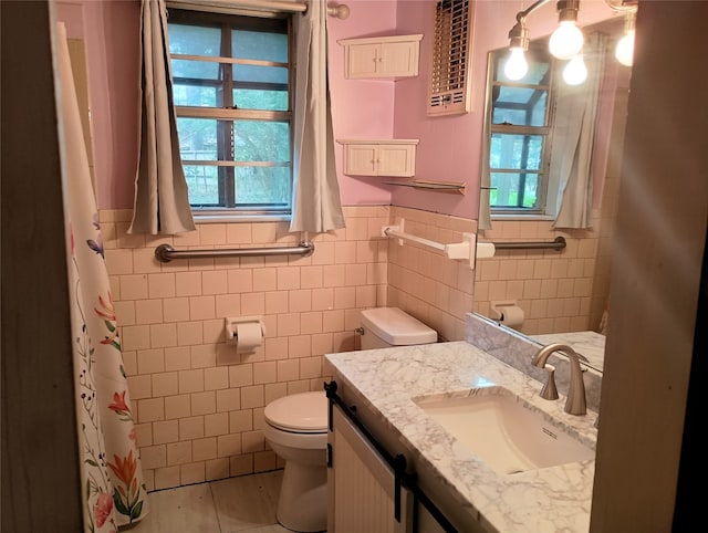 bathroom with toilet, vanity, tile patterned floors, and tile walls