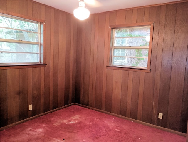 carpeted empty room featuring wooden walls