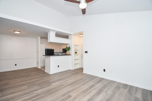 unfurnished living room with vaulted ceiling, ceiling fan, and light hardwood / wood-style flooring