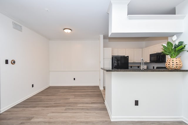 kitchen with black appliances, white cabinetry, kitchen peninsula, and light hardwood / wood-style flooring